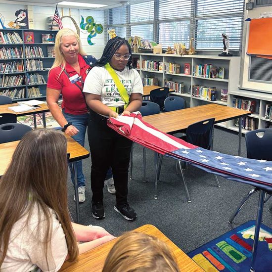 Volunteer teaching student folding flag