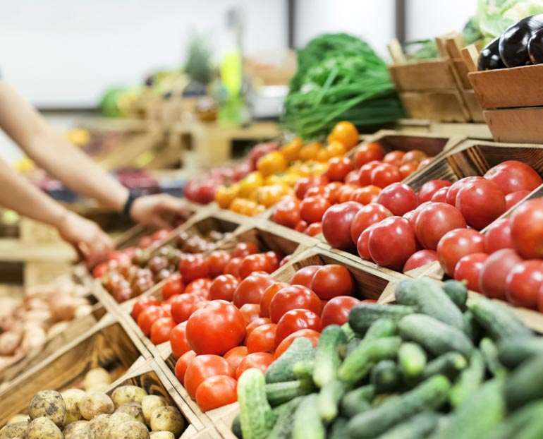 A stock image of fresh produce in wooden bins at an outdoor farmers market