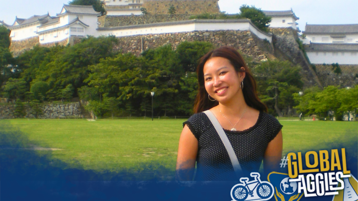 A smiling student stands in front of a historic Japanese castle and green lawn with a â#Global Aggiesâ graphic in the corner.