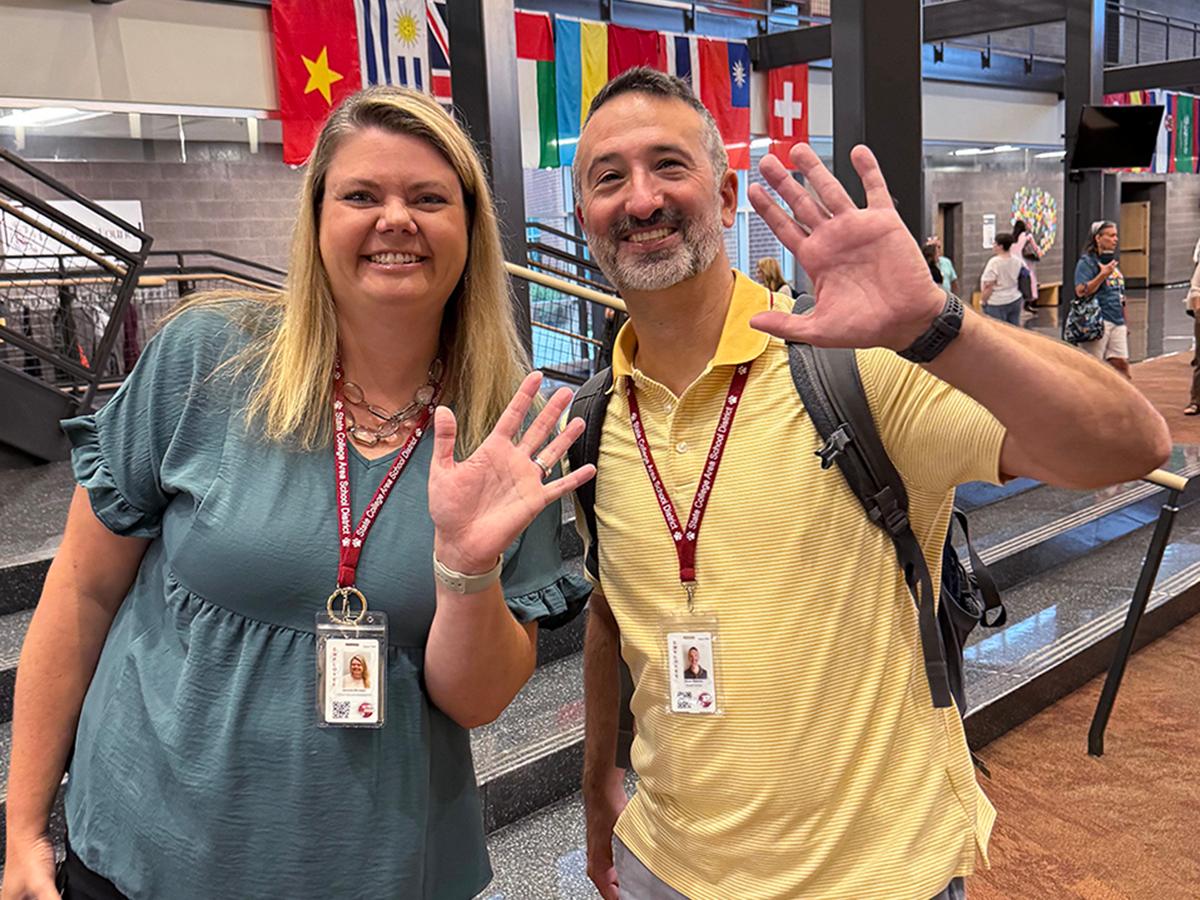 Two teachers wave hello