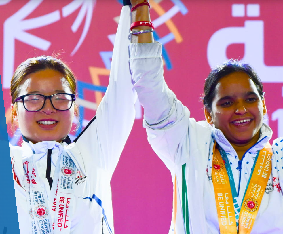Image is of two Louisiana special olympic athletes with raised joined hands with metals around their necks