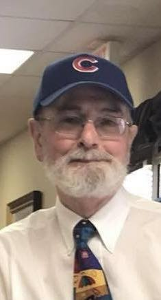 Picture is of Barry Myers wearing a white shirt with a colorful tie and cubs baseball hat and glasses with a gray beard