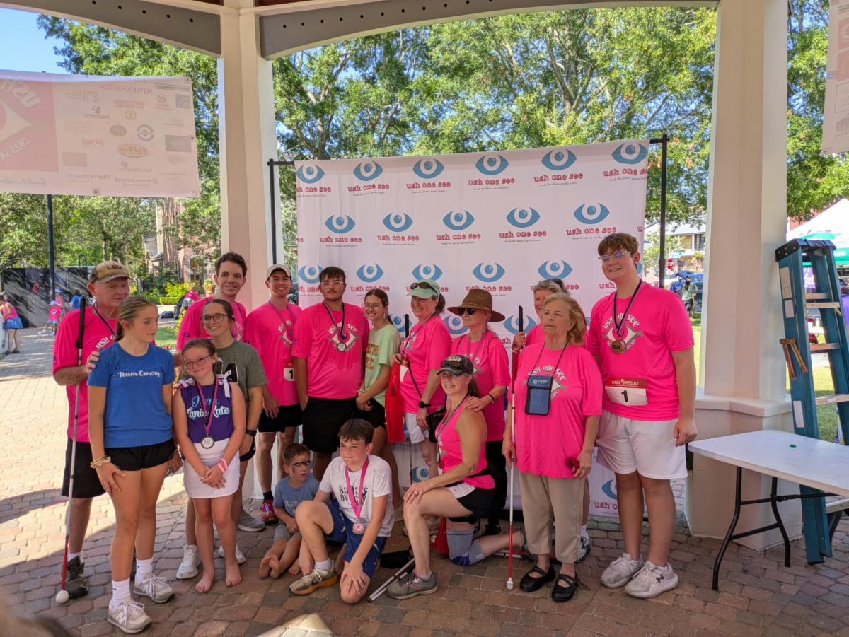 Picture is of a group of individuals in bright pink tshirts ready for the USHE one see 5k run