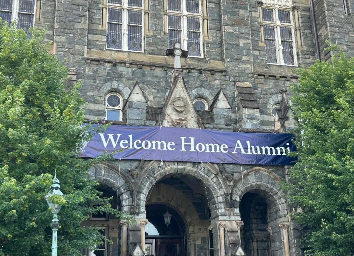 A blue banner that says Welcome Home Alumni on the outside front of Healy Hall