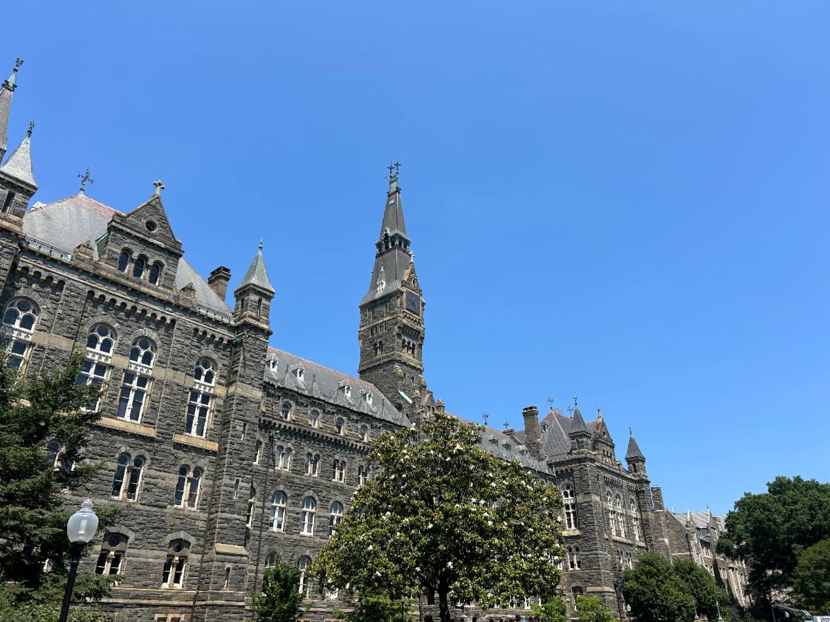 Healy Hall on Georgetown's campus with a magnolia in bloom in the foreground and a blue sky in the background