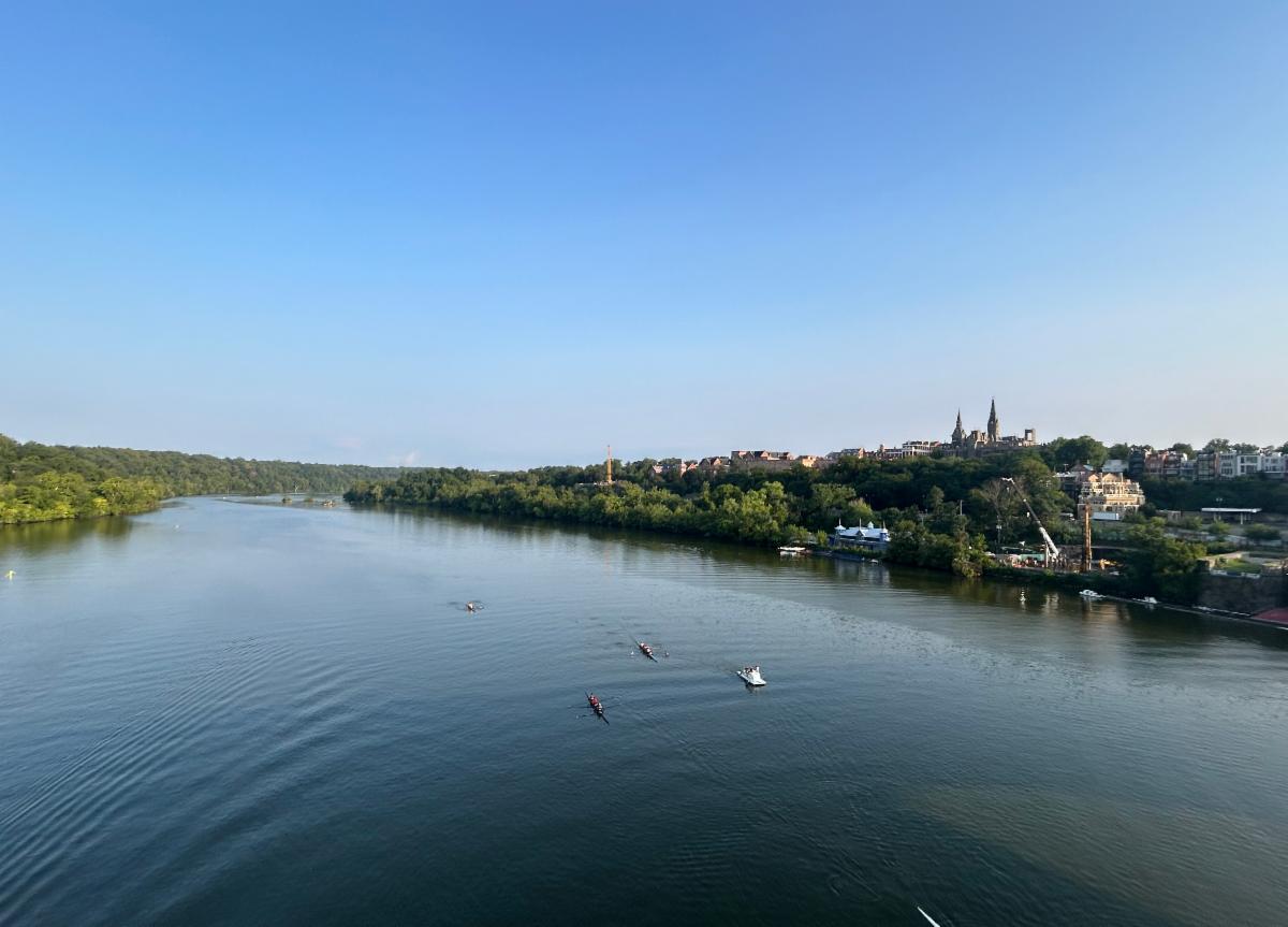 The Potomac River from the Key Bridge with blue sky and Healy Hall in distance. Photo by Cessato