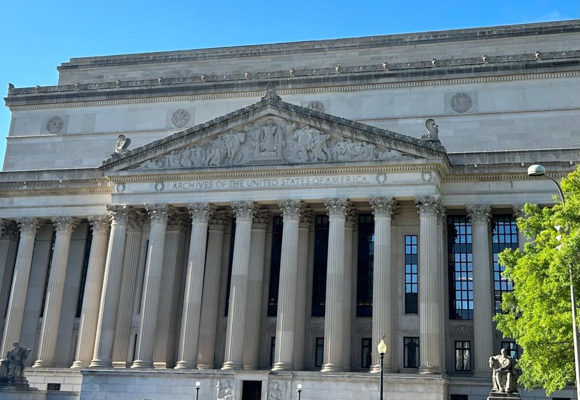 The exterior of the National Archives Building in Washington DC with a blue sky behind it