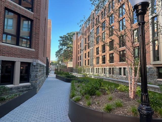 A brick and stone residence hall with a blue sky and trees 