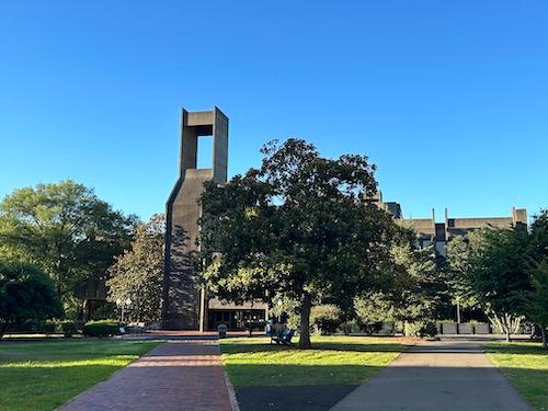 Lauinger Library on Georgetown's campus with brick sidewalk and green grass in foreground and blue sky in background