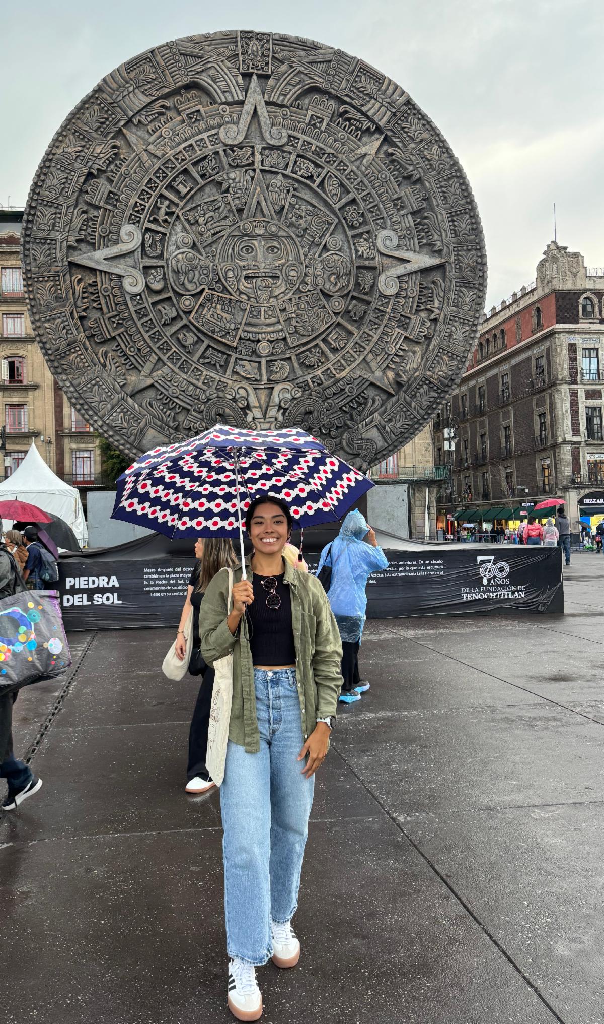 Guadalupe Avila, using an umbrella, at the Piedra del Sol