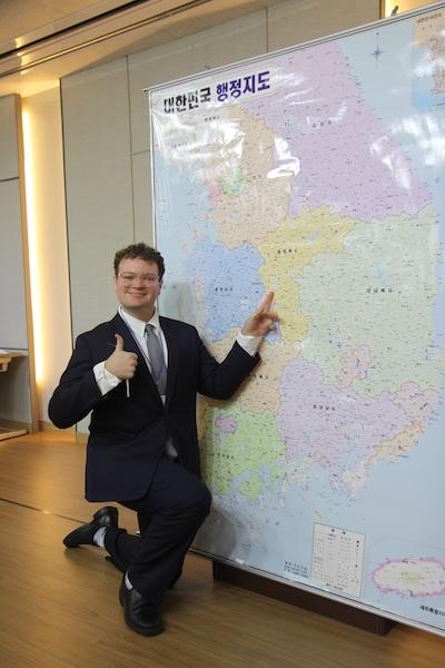 Caed Spencer, kneeling on one knee, points to a large map.
