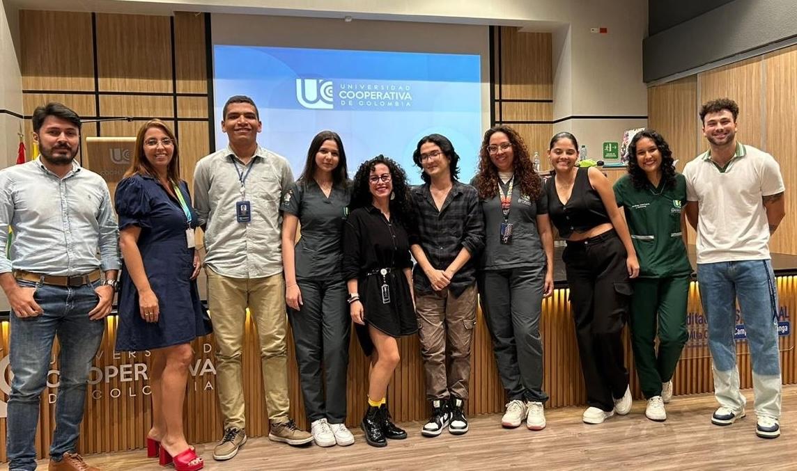 A group photo of people standing in front of a stage and a movie screen