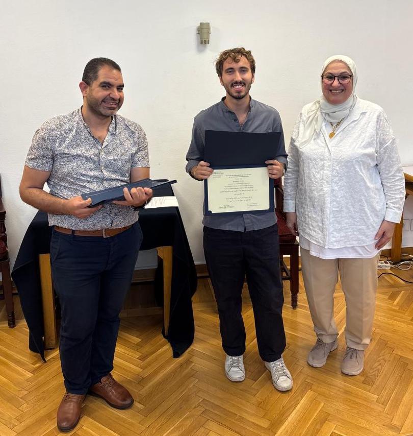 Group indoor photo of Max Levine (holding a certificate) with Dr. Azza Hassanein and Hany Serafeen, the director and the administrator of the program