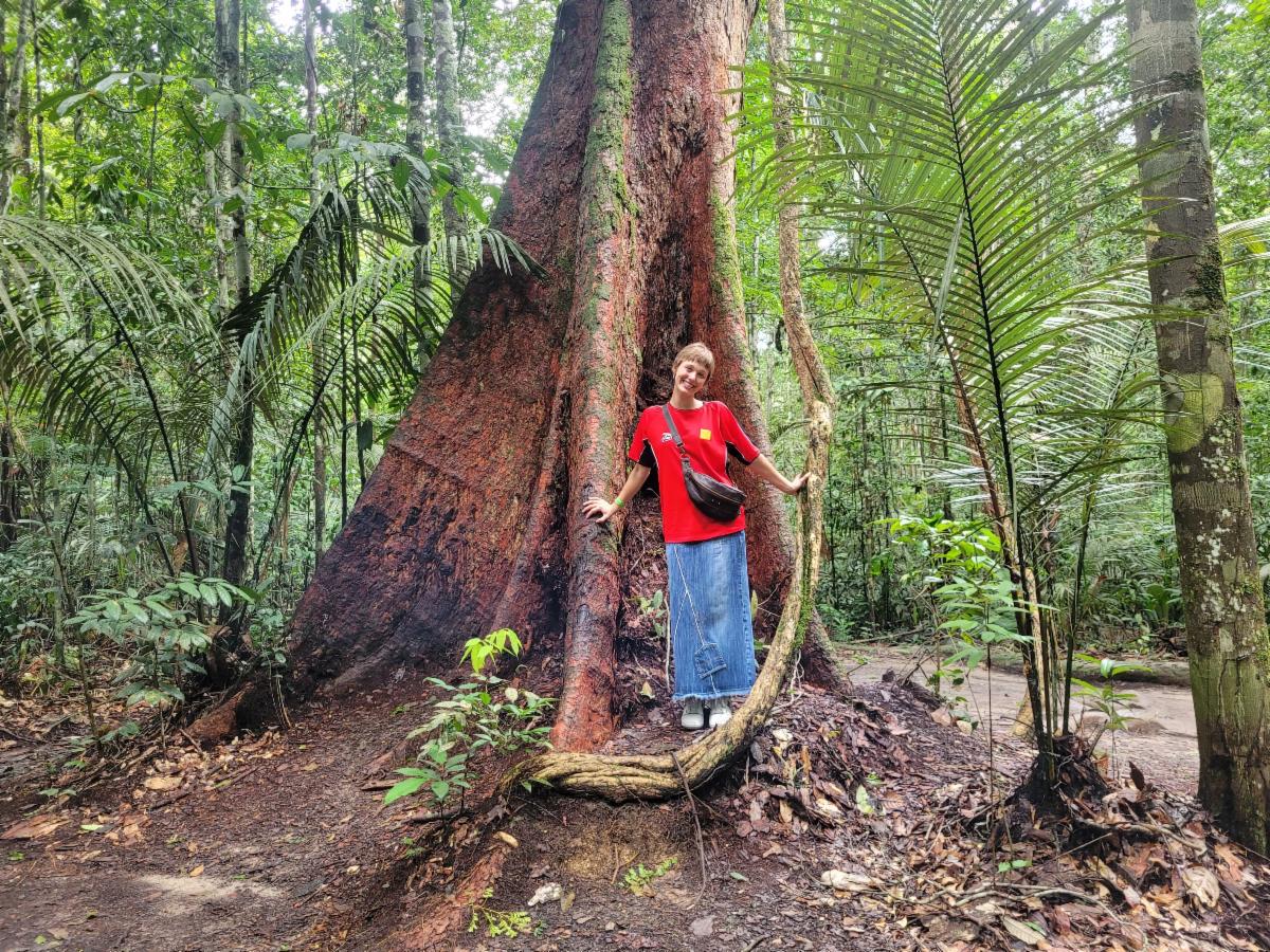 Alexandra Meger stands in front of a tree in a forest