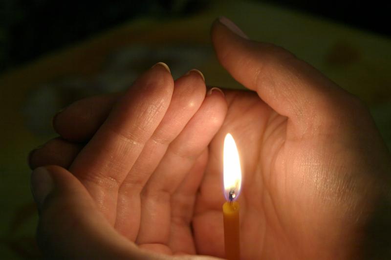 lighting candle in womans hand. dark tone.
