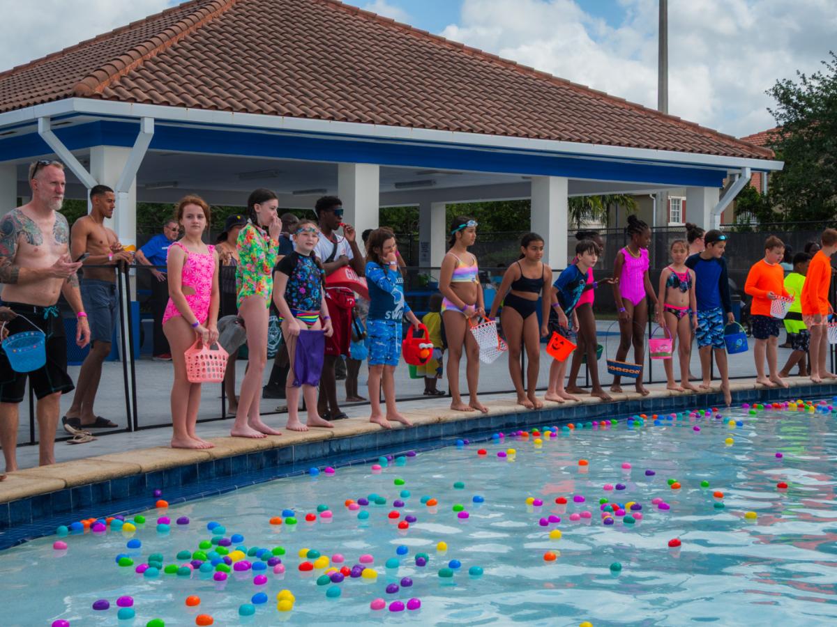 Persons standing out a pool holding colorful baskets 