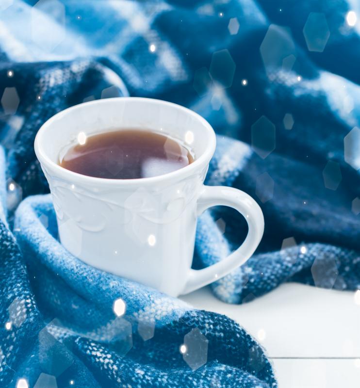 Beautiful white cup of hot tea and a blue checkered woolen plaid. Cozy winter home arrangement.