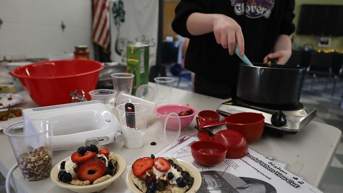 A young person making food, various utensils and dishes around them.