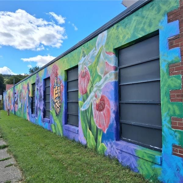 A long brick wall mural of flowers and butterflies.