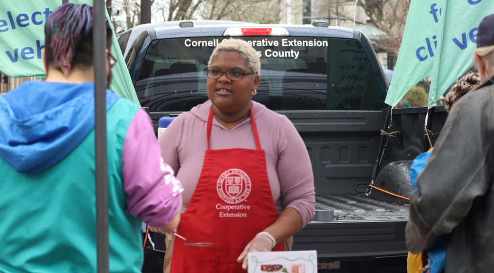 A person in a cooperative extension apron talking with an Earth Day participant.