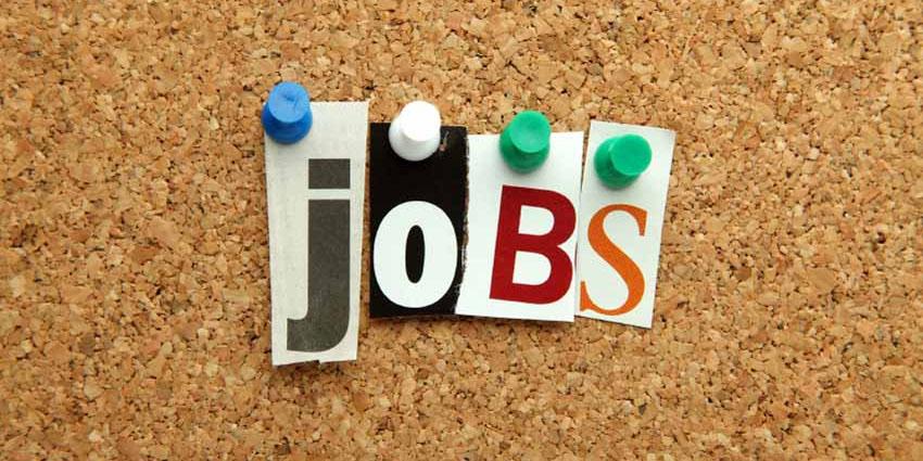 cutout letters spelling Jobs held with push pins on a cork board