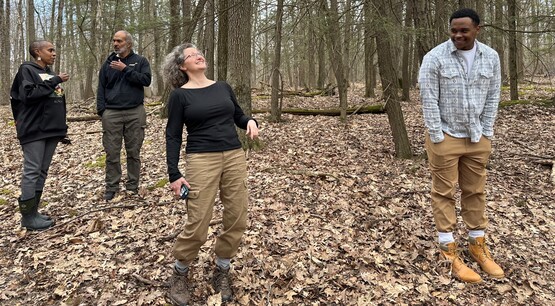 Four people standing in a forest.
