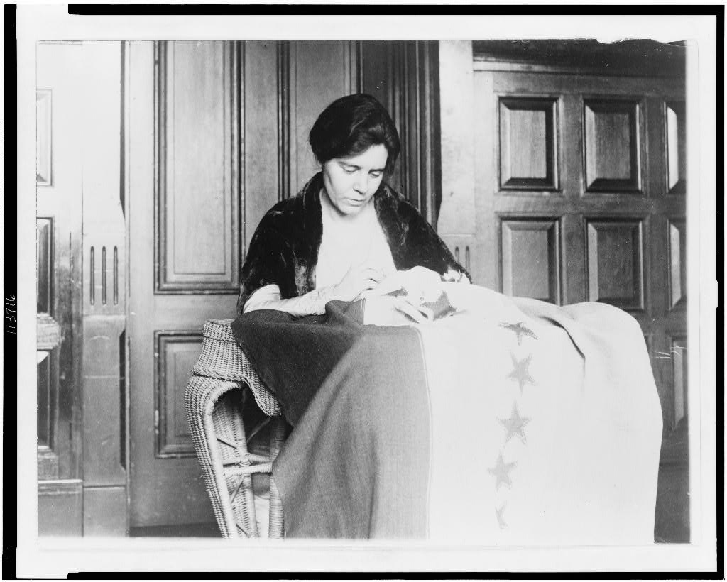 Suffragist leader Alice Paul sews stars onto the ratification banner.